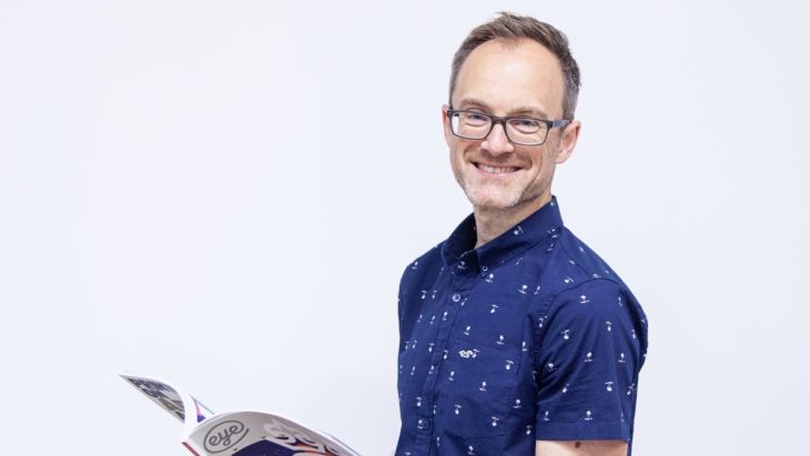 Head shot of James smiling holding a book