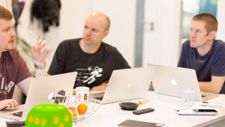 A photo 3 people in a meeting with their laptops