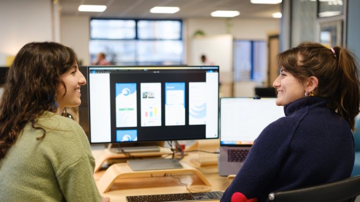 Elle and Annie smile at each other whilst working on the UX design of an app