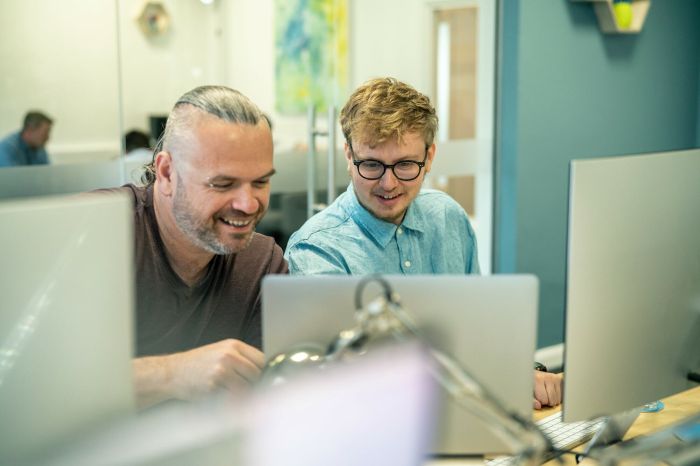 Steve Johnson and Rhys Kentish working together at their desks in the office