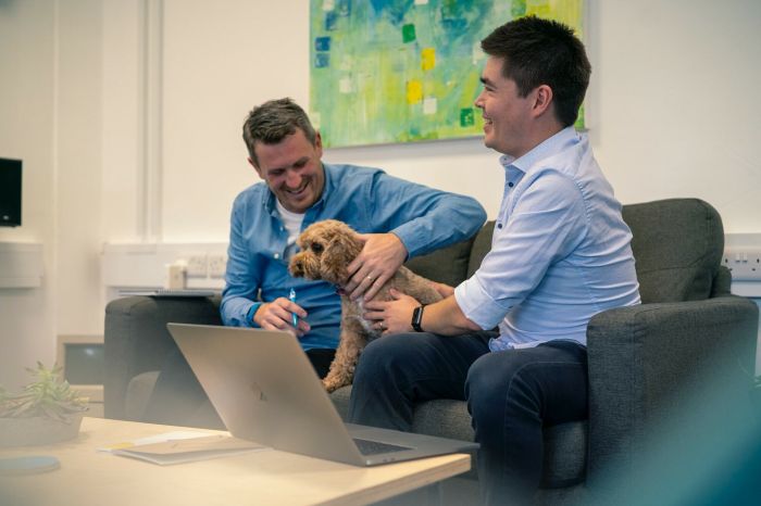 Andy Ferret and Dave Thompson sitting on the meeting room sofa with cookie the dog