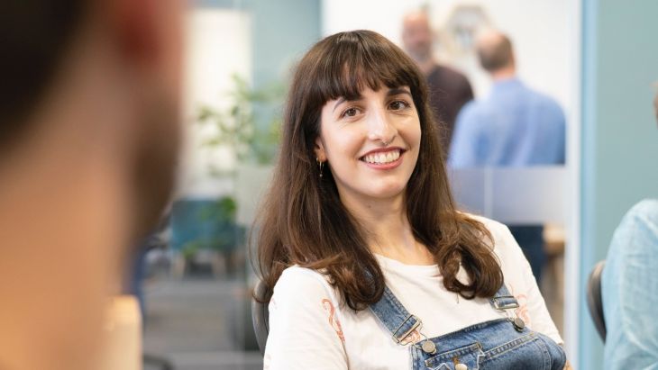 A photo of Elle smiling in conversation with a team member